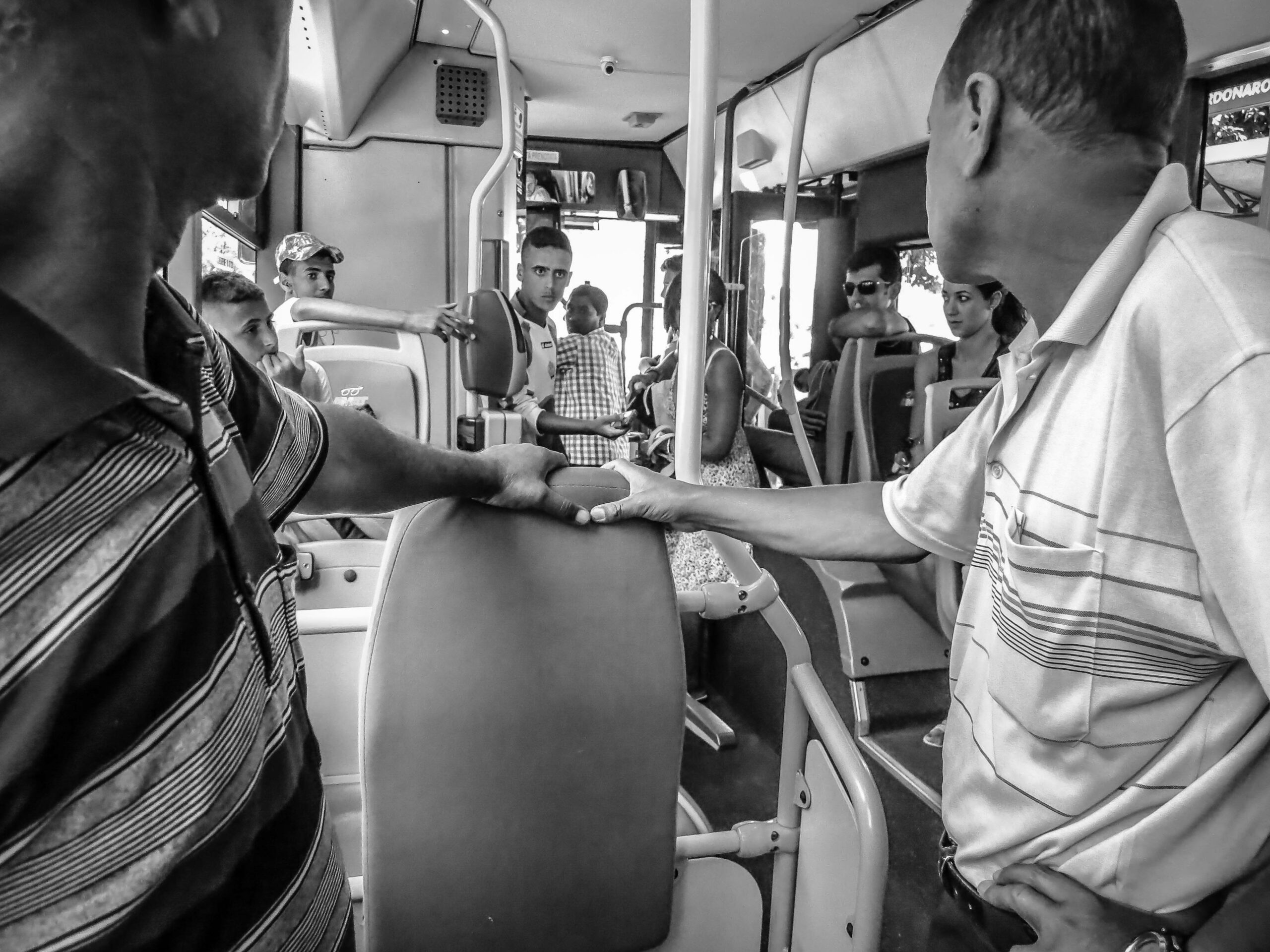 Image of men staring at each other on a train with some tension.