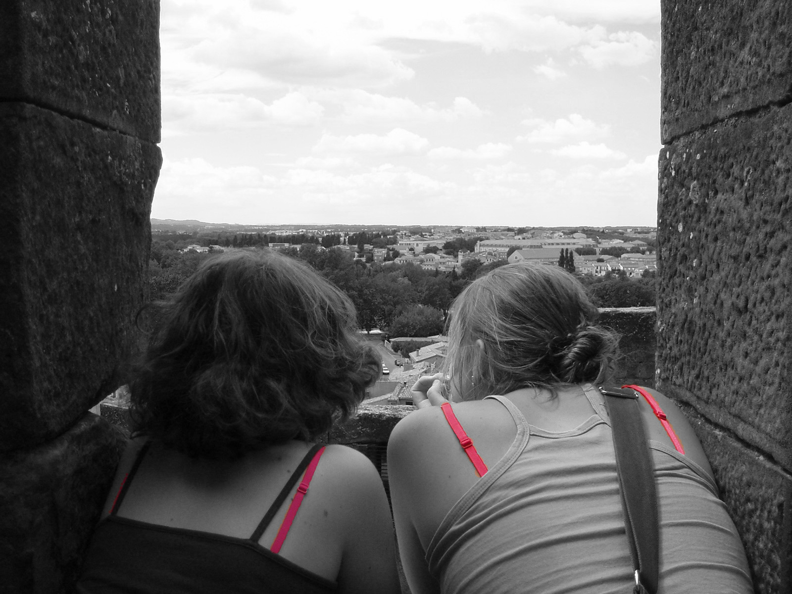 Black and white image of two women looking out a window.