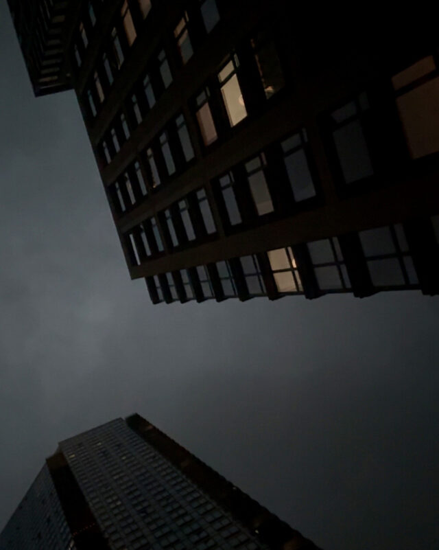 Photograph of night sky framed by two skyscrapers seen from below.