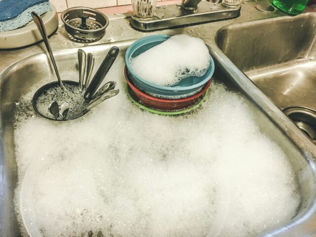 Photograph of a kitchen sink full of dishes.
