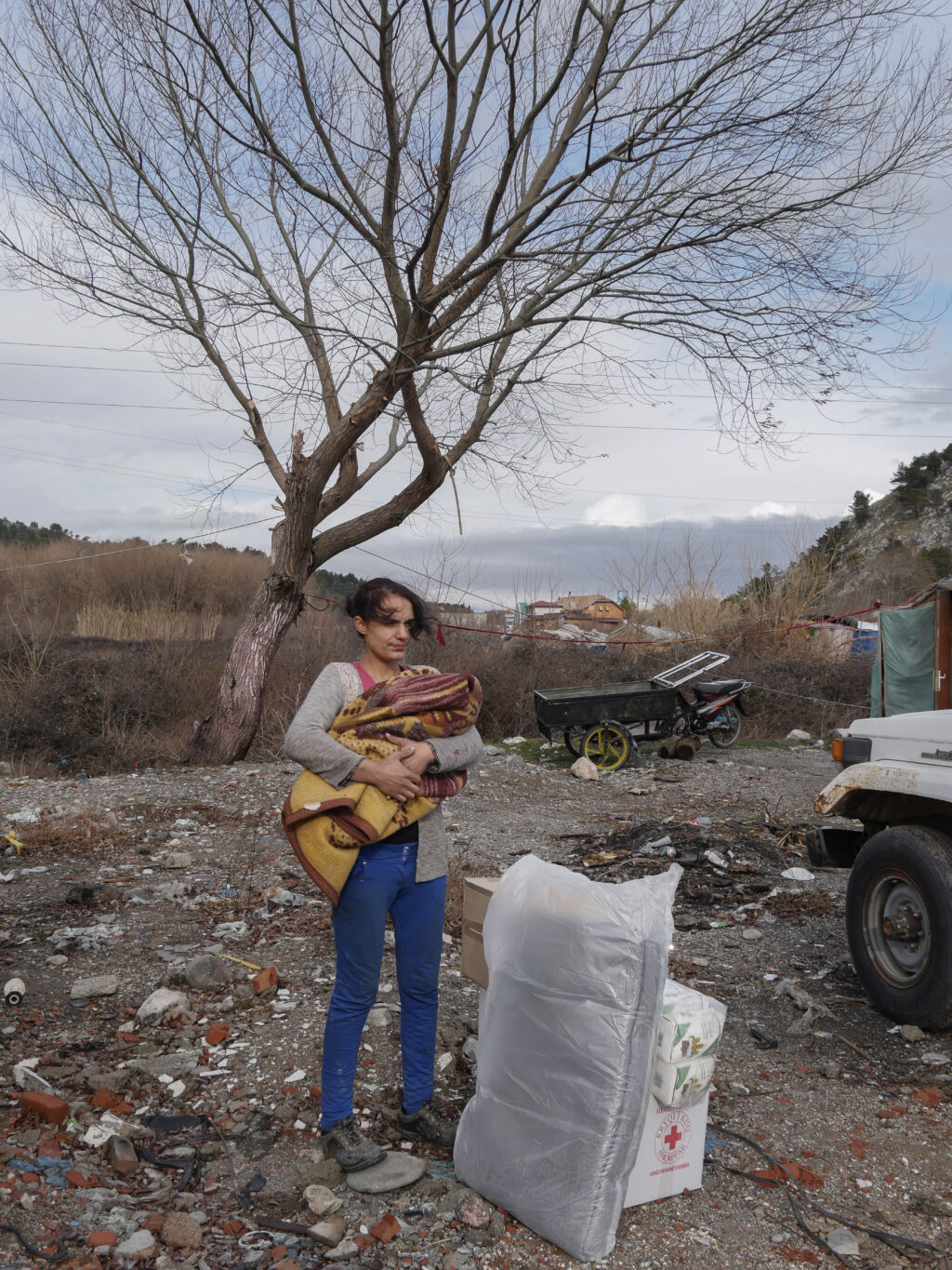 Photograph, possibly in Albania, of a woman in a barren landscape, with her hair swept by the wind.