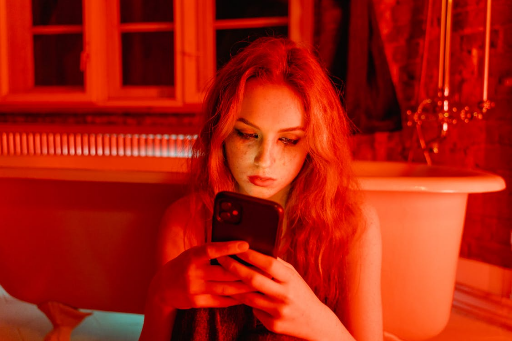 Image of young woman looking at her phone in an obsessive manner.