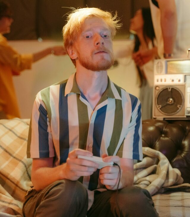 Image of a young man playing a video game with an intense expression on his face.