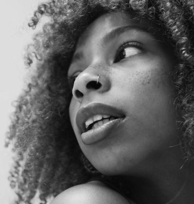 Close-up photograph of a young black woman looking over her shoulder.